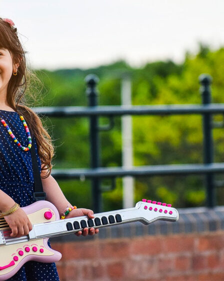 Une petite fille avec sa guitare jouet rose
